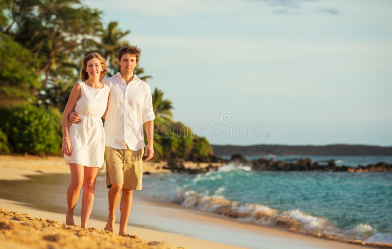 Young couple in love walking on the beach at sunset stock photo