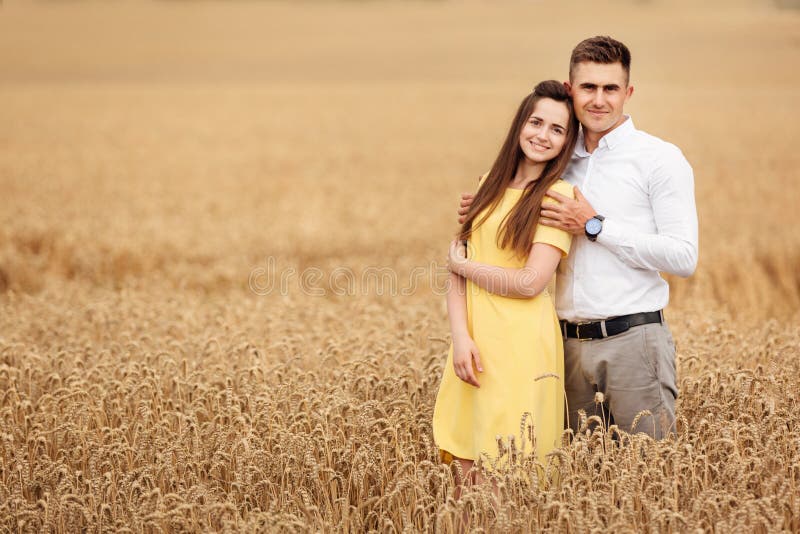 A young couple of lovers woman and man hugging in nature, in a yellow wheat field. The concept of love, good relationships