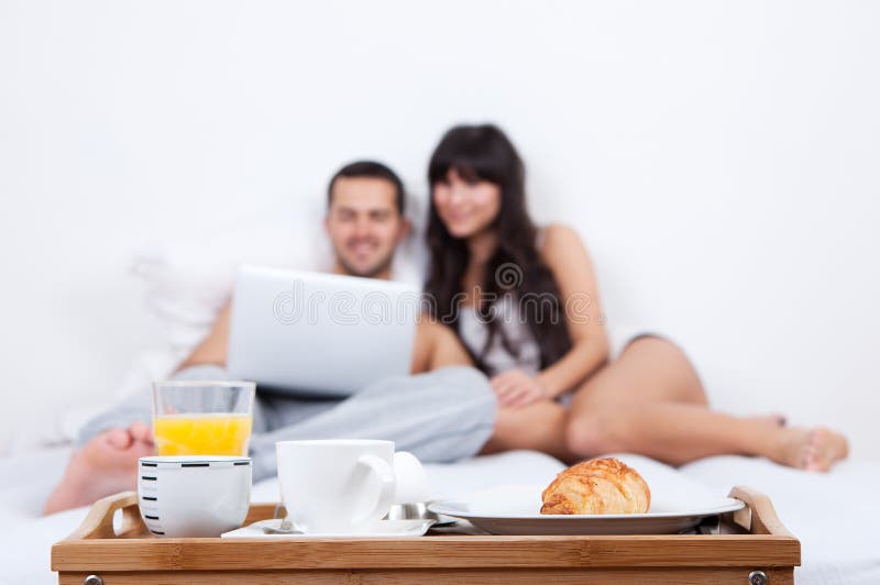 Young couple lying up in bed with laptop stock photo