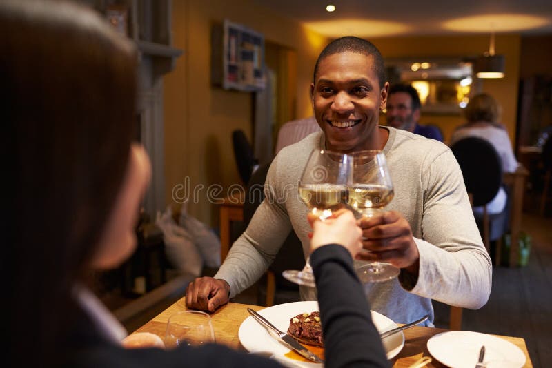 Young couple make a toast at restaurant, over-shoulder view