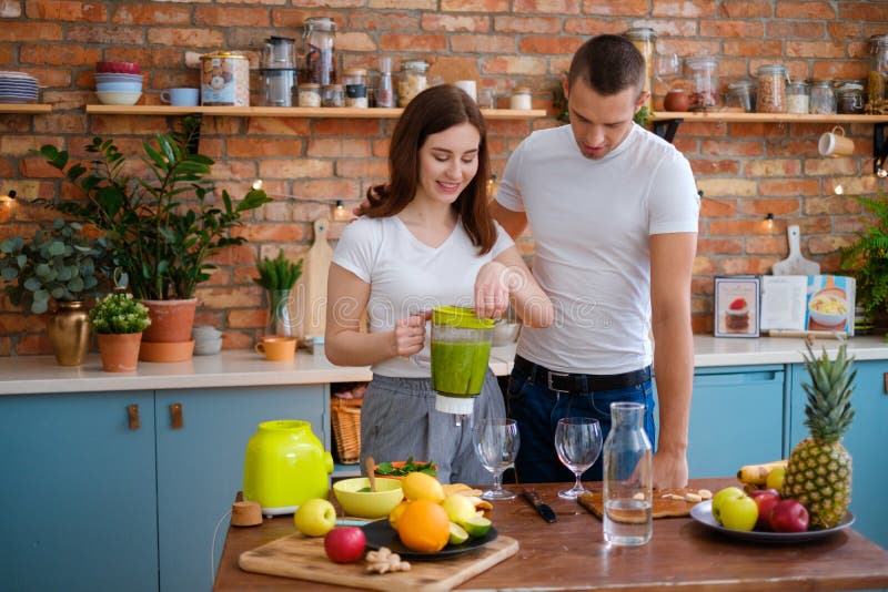 Young couple making smoothie in kitchen