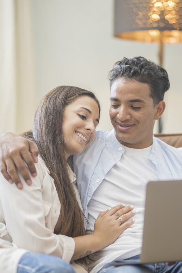 Young couple moving to a new home relaxing sitting on the sofa using computer laptop, smiling happy for moving to new apartment royalty free stock photography