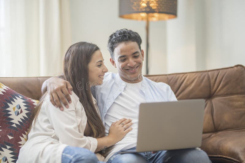 Young couple moving to a new home relaxing sitting on the sofa using computer laptop, smiling happy for moving to new apartment royalty free stock photo
