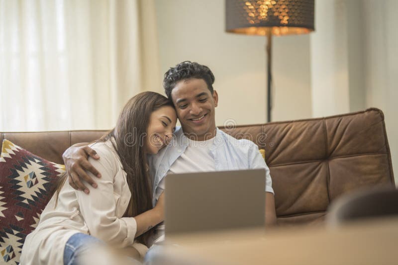 Young couple moving to a new home relaxing sitting on the sofa using computer laptop, smiling happy for moving to new apartment royalty free stock images