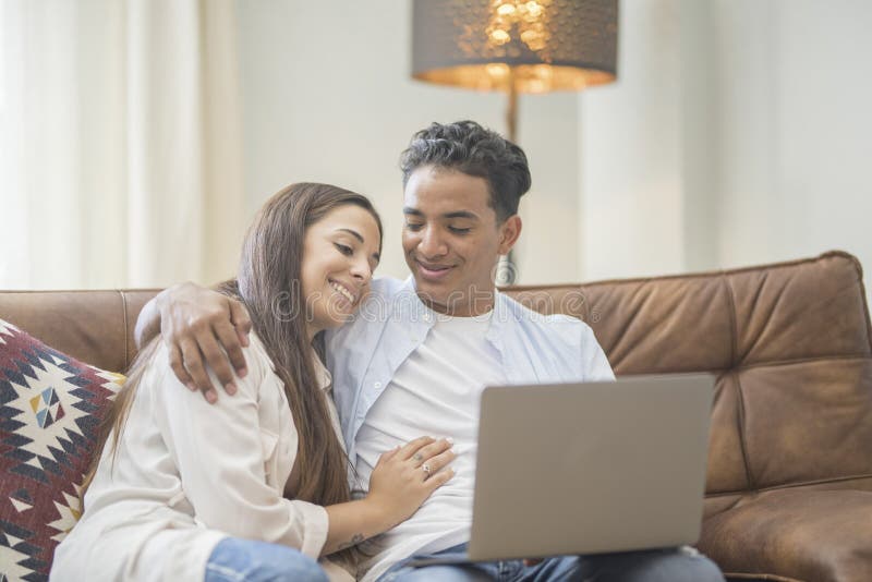 Young couple moving to a new home relaxing sitting on the sofa using computer laptop, smiling happy for moving to new apartment royalty free stock photography
