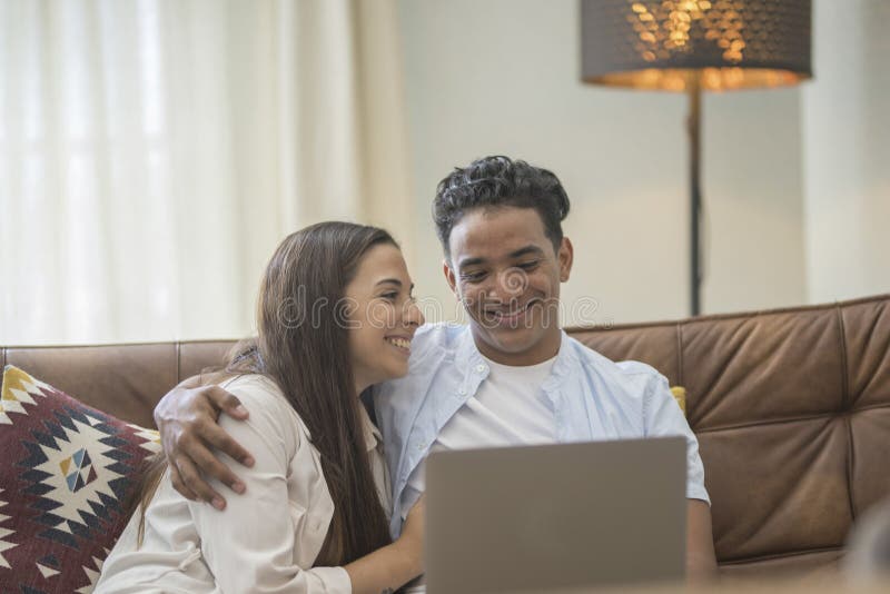 Young couple moving to a new home relaxing sitting on the sofa using computer laptop, smiling happy for moving to new apartment stock photos