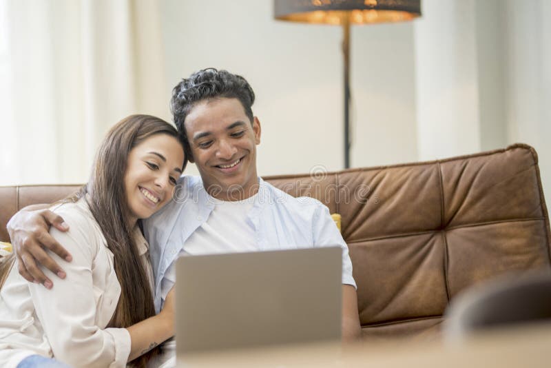 Young couple moving to a new home relaxing sitting on the sofa using computer laptop, smiling happy for moving to new apartment royalty free stock images