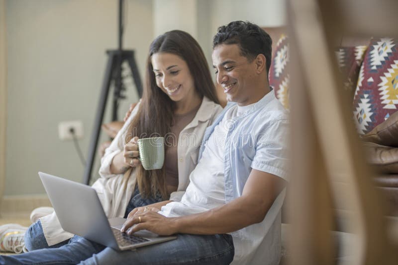 Young couple moving to a new home relaxing sitting on the sofa using computer laptop, smiling happy for moving to new apartment stock image