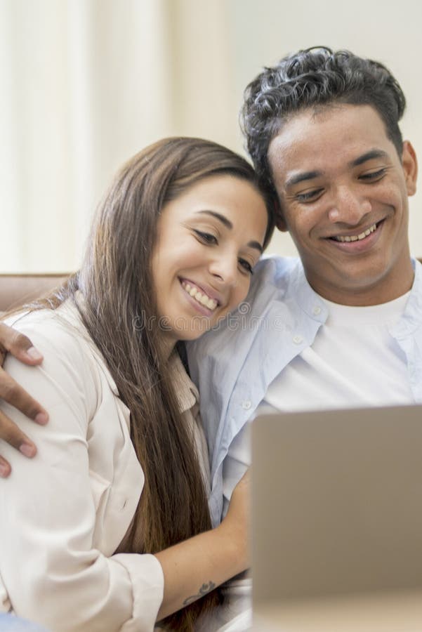 Young couple moving to a new home relaxing sitting on the sofa using computer laptop, smiling happy for moving to new apartment stock image