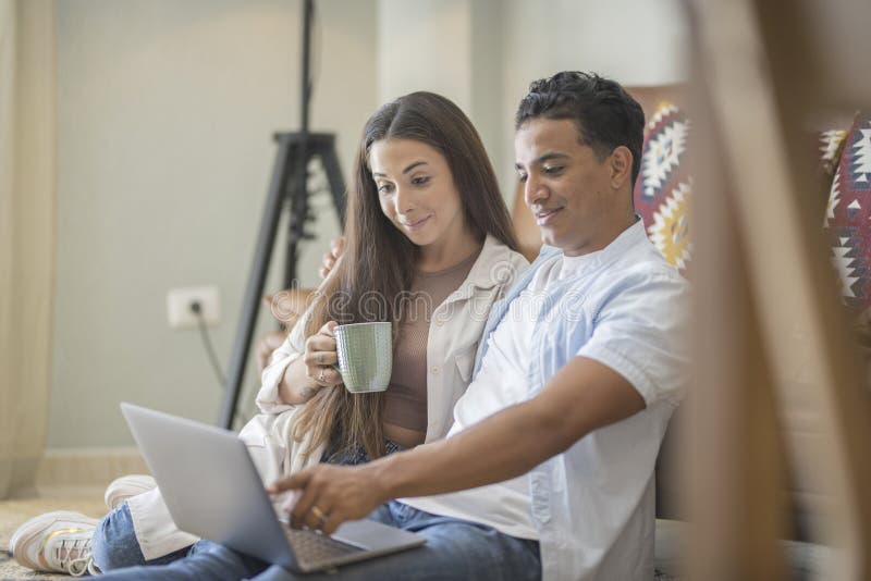 Young couple moving to a new home relaxing sitting on the sofa using computer laptop, smiling happy for moving to new apartment royalty free stock images