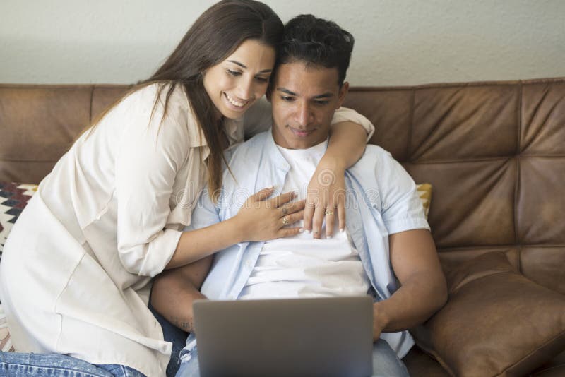 Young couple moving to a new home relaxing sitting on the sofa using computer laptop, smiling happy for moving to new apartment stock image