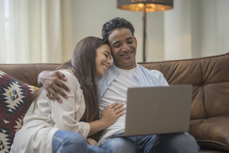 Young couple moving to a new home relaxing sitting on the sofa using computer laptop, smiling happy for moving to new apartment stock photo