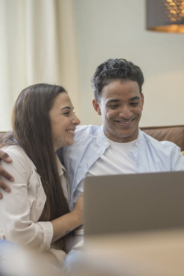 Young couple moving to a new home relaxing sitting on the sofa using computer laptop, smiling happy for moving to new apartment stock photography