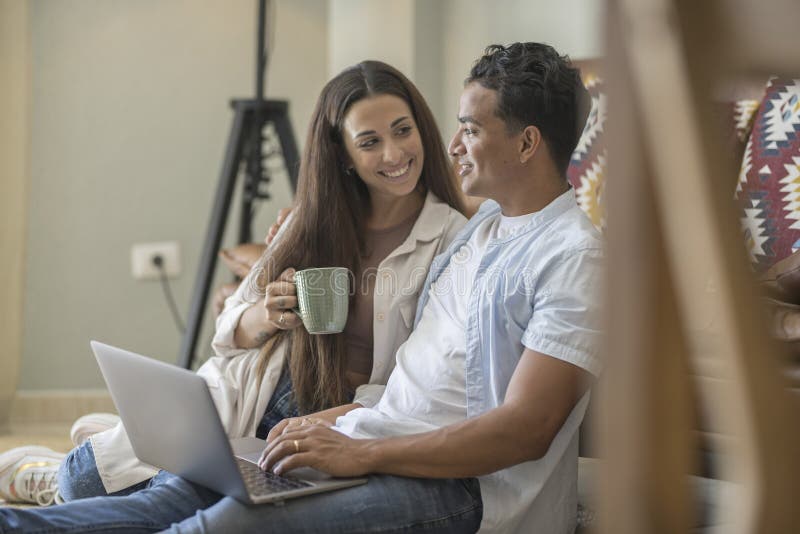 Young couple moving to a new home relaxing sitting on the sofa using computer laptop, smiling happy for moving to new apartment stock images