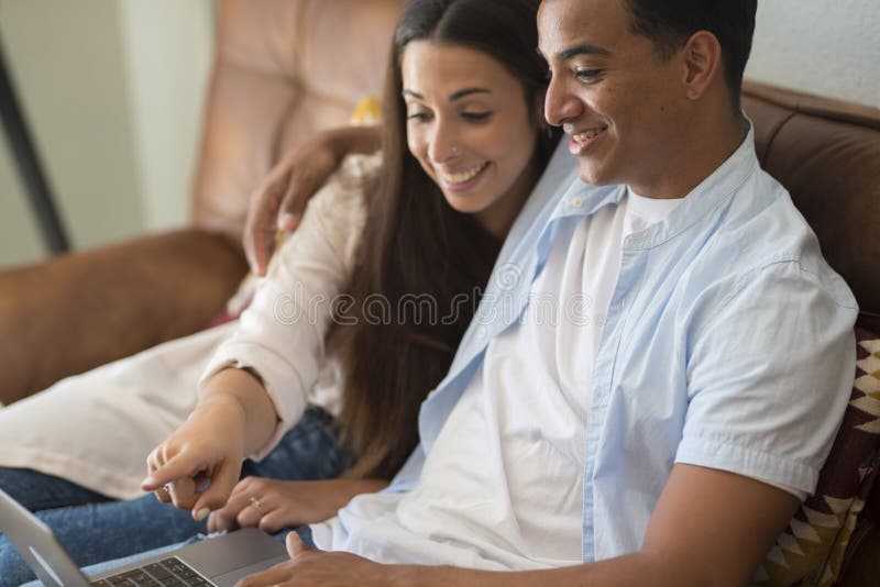 Young couple moving to a new home relaxing sitting on the sofa using computer laptop, smiling happy for moving to new apartment stock image
