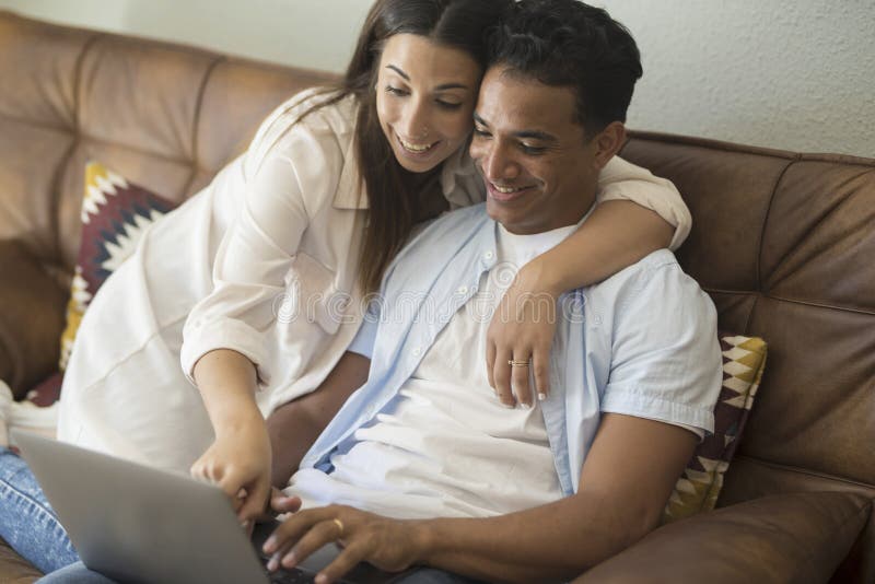 Young couple moving to a new home relaxing sitting on the sofa using computer laptop, smiling happy for moving to new apartment royalty free stock photos