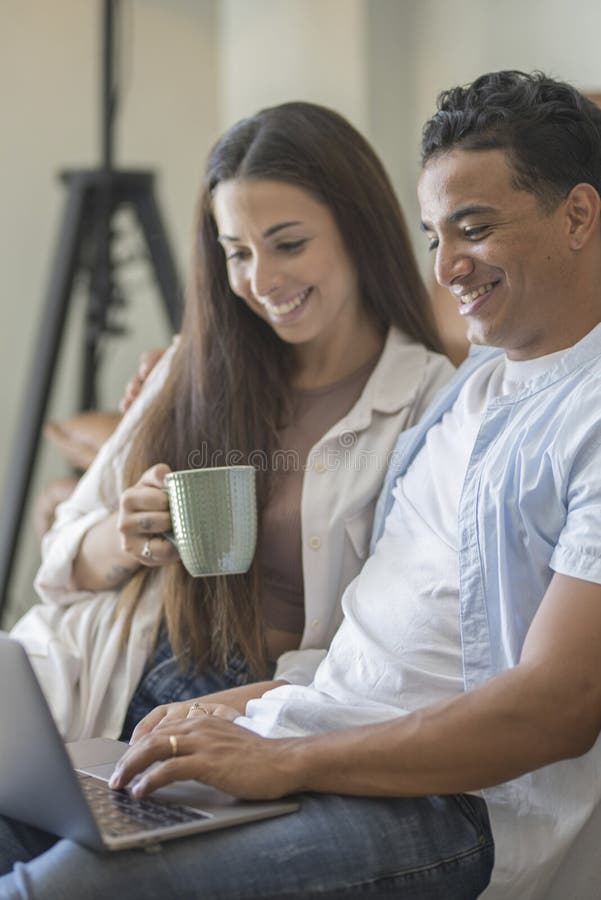 Young couple moving to a new home relaxing sitting on the sofa using computer laptop, smiling happy for moving to new apartment stock images
