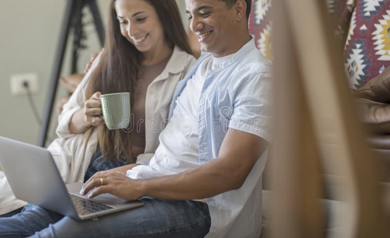 Young couple moving to a new home relaxing sitting on the sofa using computer laptop, smiling happy for moving to new apartment stock photo