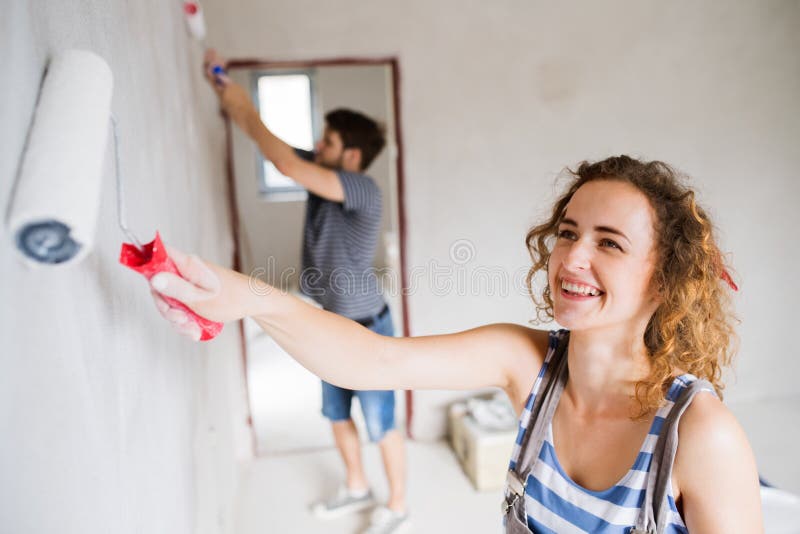 Young couple painting walls in their new house.