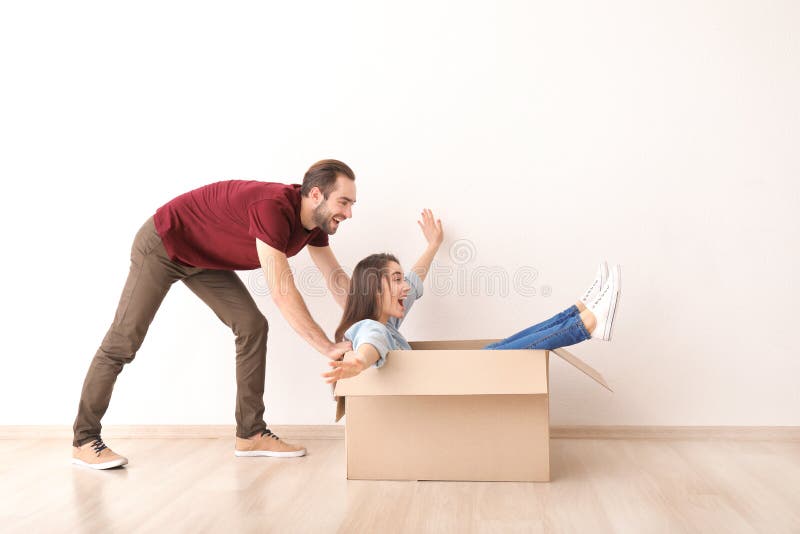 Young couple playing with box indoors. Moving into new house