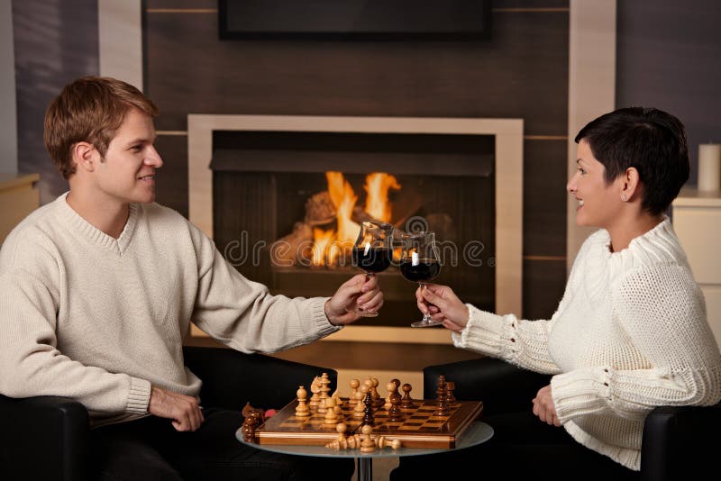 Focused man sipping alcoholic beverage while thinking about next chess move.  Stock Photo by DC_Studio