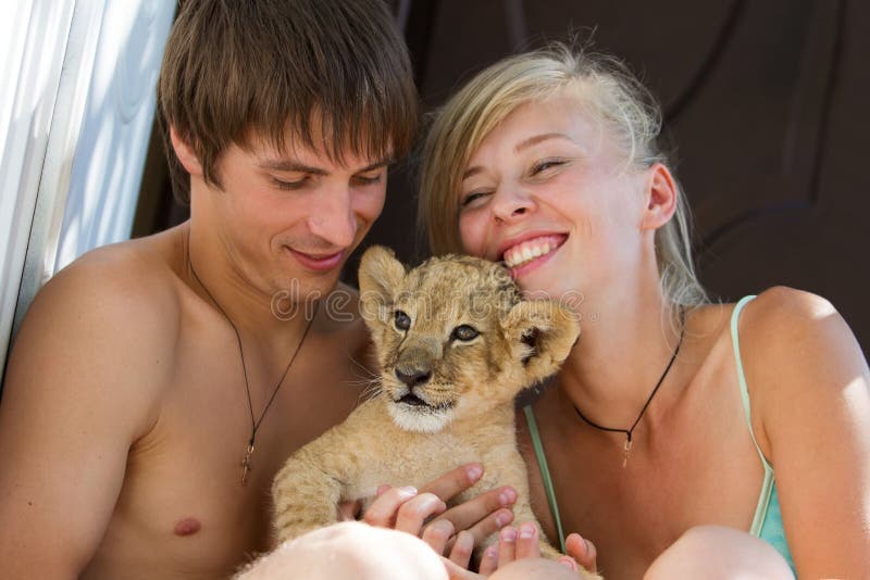 Young couple playing with little lion cub