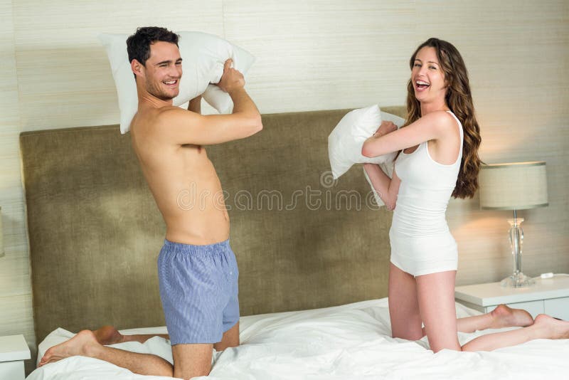 Young couple playing pillow fight