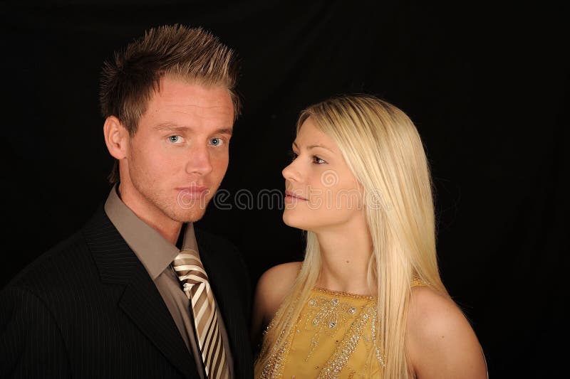 A formal portrait of a young couple on a black background. A formal portrait of a young couple on a black background.