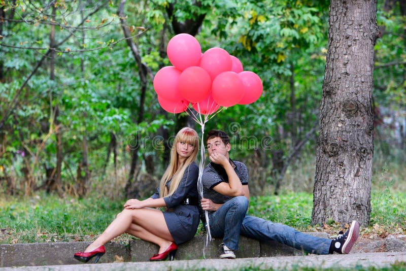 Young couple with red balloons on nature