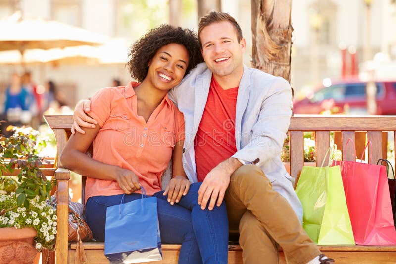 Young Couple Resting With Shopping Bags Sitting In Mall