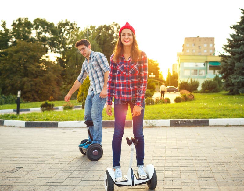 Young couple riding hoverboard - electrical scooter, personal ec