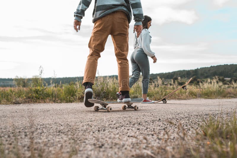 Young Couple Riding a Skateboard on a Road. Concept of Millenials ...