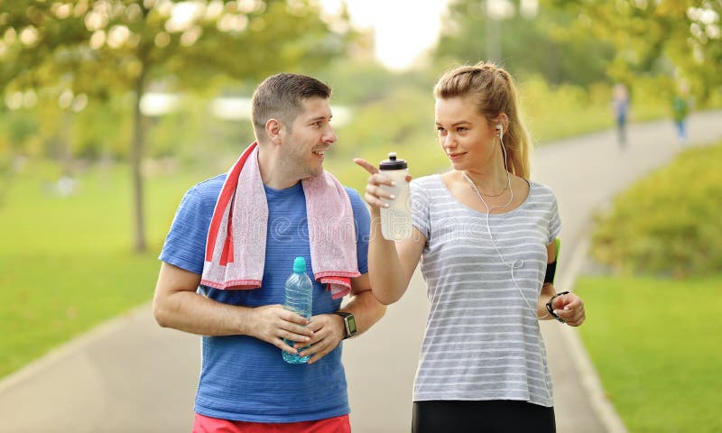 Young couple running and chatting in city park. Cheerful caucasian modern man and woman in headsets jogging in nature and living stock photos Young couple running and chatting in city park. Cheerful caucasian modern man and woman in headsets jogging in nature and living stock photos