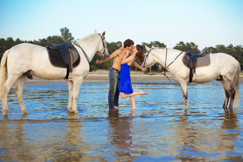 Young couple in the sea with horses