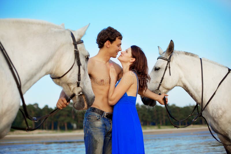 Young couple in the sea with horses