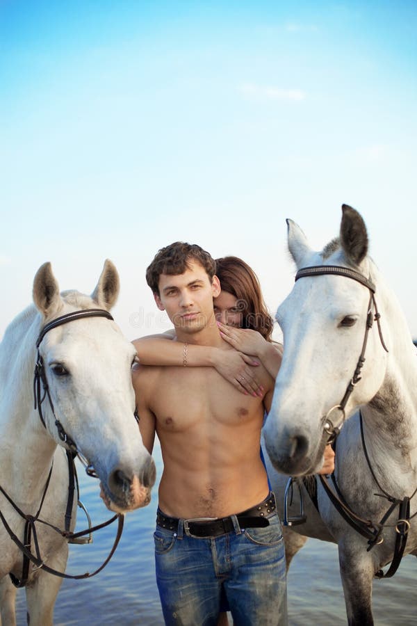 Young couple in the sea with horses