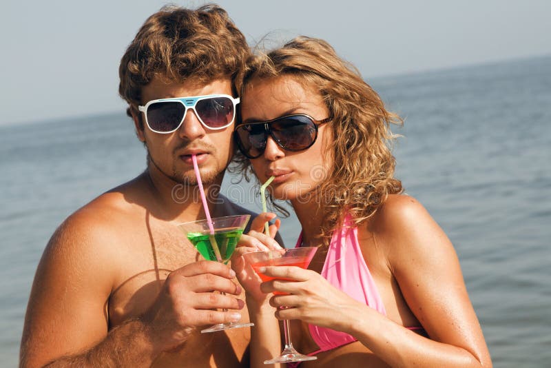 Young couple on the seaside with cocktails