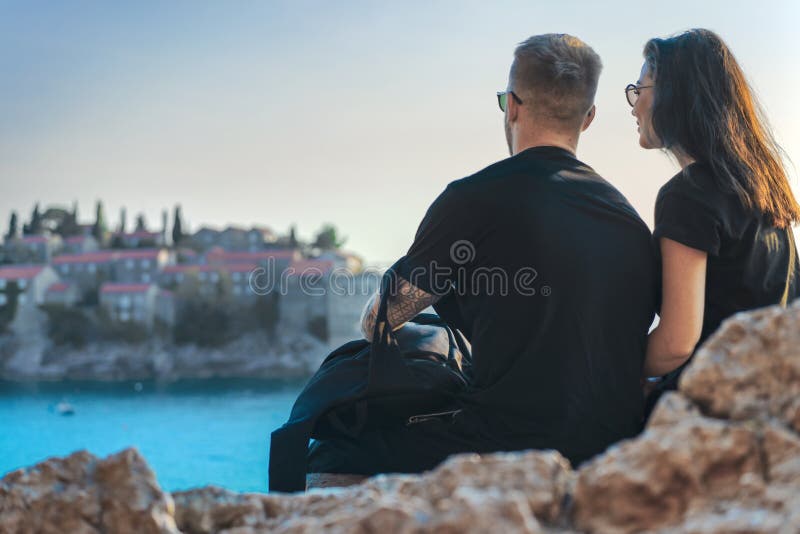 Young couple sitting on cliff above sea and looking at european town on island royalty free stock photo Young couple sitting on cliff above sea and looking at european town on island royalty free stock photo