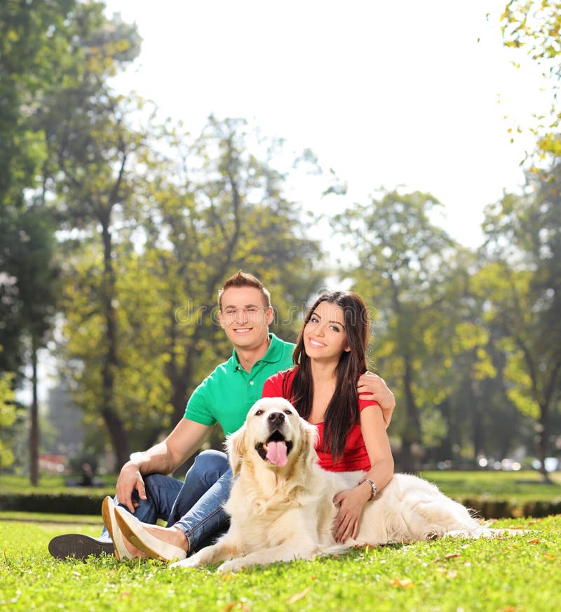 Young couple sitting in park with a dog