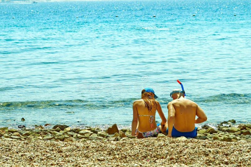 Young couple sitting on the shore of the red sea stock photo Young couple sitting on the shore of the red sea stock photo