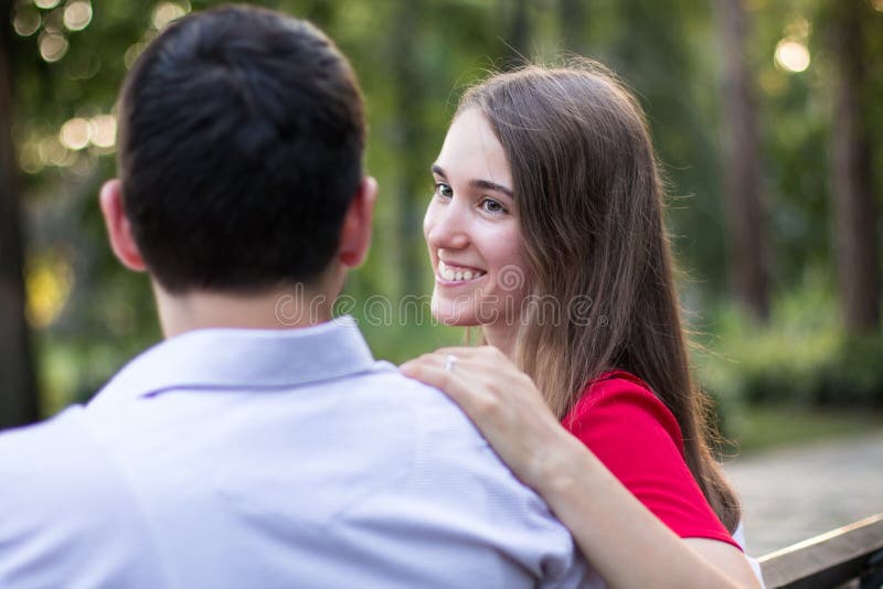 Young couple sitting together on a bench in the park.