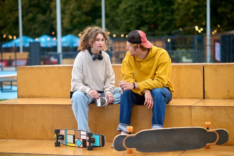 Young couple of skateboarders sitting on the bench and talking royalty free stock image