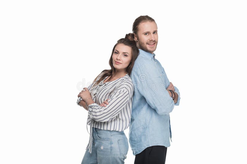 Young couple standing back to back and smiling at camera