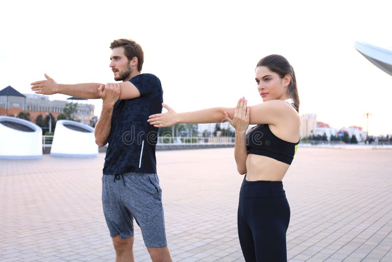 Young couple stretching muscles on urban street at sunset stock images Young couple stretching muscles on urban street at sunset stock images