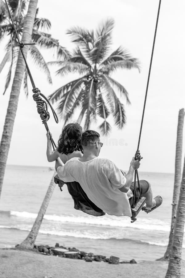 Young couple swinging on the tropical beach of Bali island, Indonesia.
