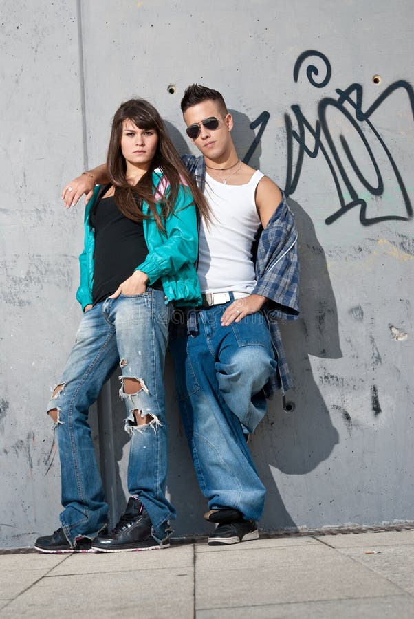 Young couple urban fashion portrait standing over wall. Young couple urban fashion portrait standing over wall