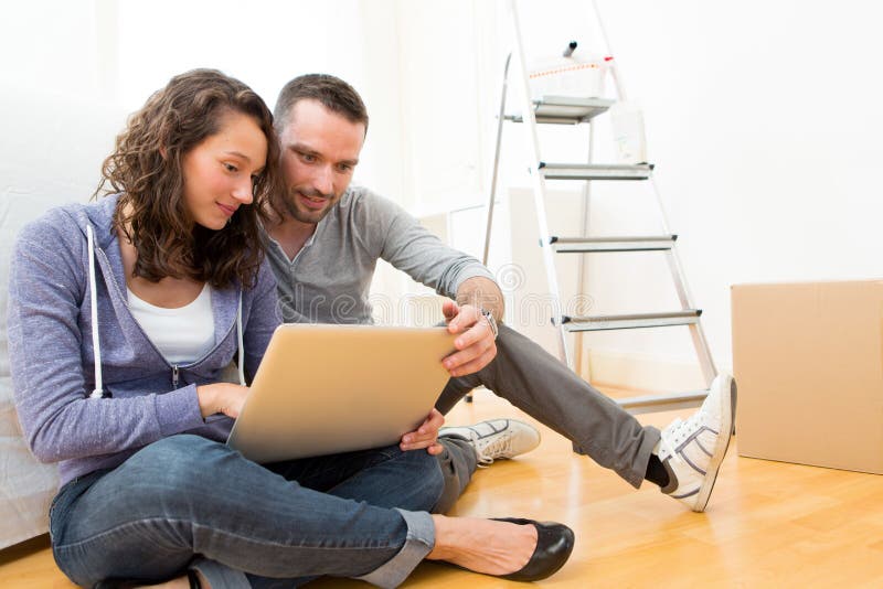 Young couple using laptop while moving in new flat stock images Young couple using laptop while moving in new flat stock images