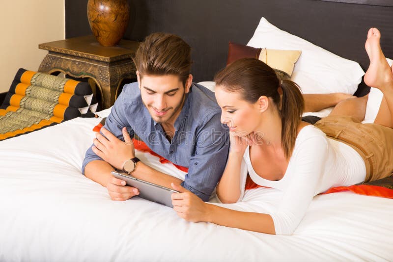 Young Couple Using a Tablet PC in a Asian Hotel Room Stock Photo
