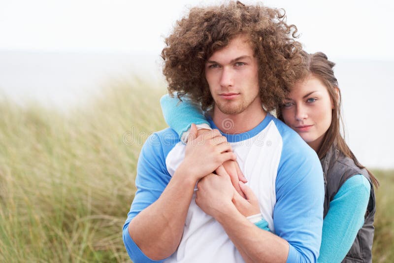 Young Couple Walking Through Sand Dunes Wearing Warm Clothing