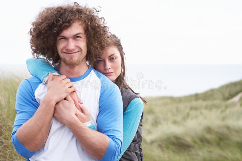 Young Couple Walking Through Sand Dunes Wearing Warm Clothing